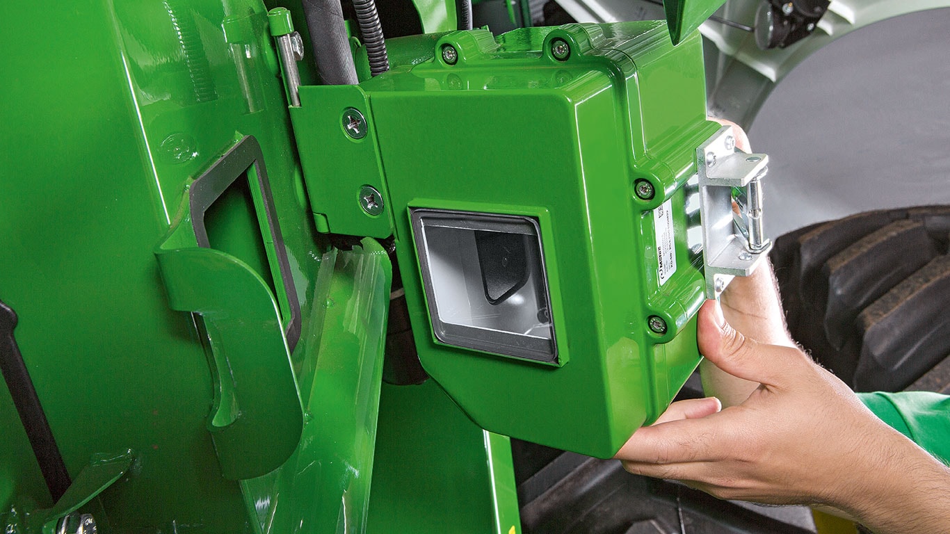 Una persona instala un componente electrónico en el marco de una maquinaria, mostrando precisión en el ensamblaje de equipos agrícolas.